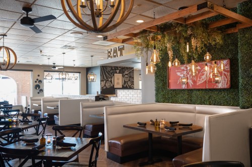 Cozy restaurant interior with booths, pendant lights, and greenery on the walls, creating a warm dining atmosphere.