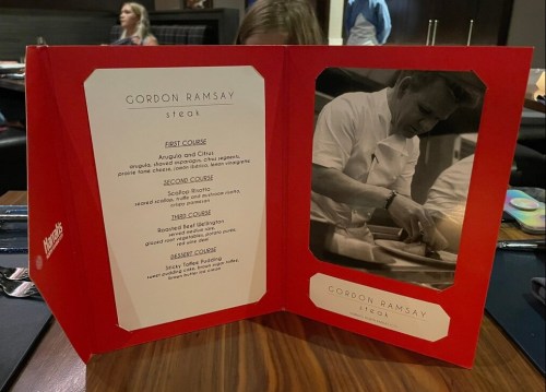 A red menu for Gordon Ramsay Steak featuring courses and a photo of Gordon Ramsay cooking.
