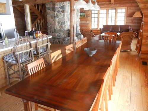 A spacious wooden dining area with a long table, chairs, and a cozy seating area in a rustic log cabin.