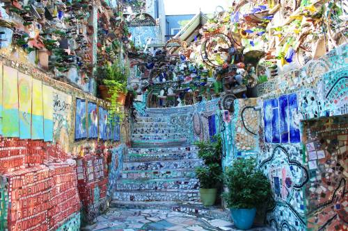 Colorful mosaic staircase surrounded by vibrant art and decorations, creating a whimsical and artistic atmosphere.