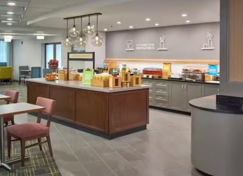 Modern kitchen area with a central island, seating, and a variety of food and drink options displayed on counters.