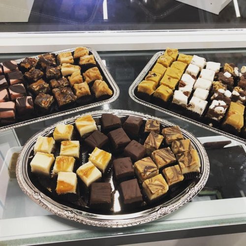 A variety of colorful, assorted chocolates and fudge pieces arranged on silver trays.