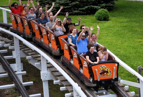 A group of excited people on a roller coaster, raising their hands in joy as they ride along the track.