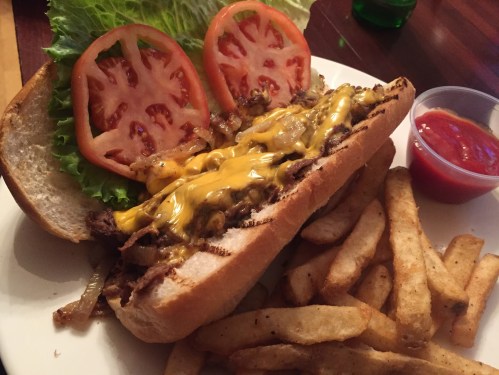 A hearty sandwich with melted cheese, lettuce, and tomatoes, served with a side of golden fries and ketchup.