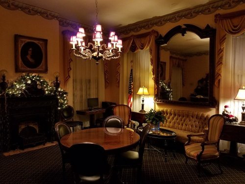 A cozy room with a chandelier, fireplace, and elegant furnishings, decorated for the holidays.
