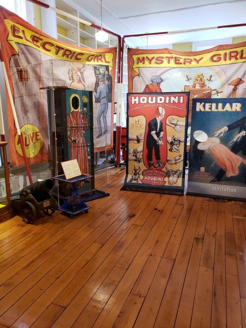 A vintage magic exhibit featuring posters of Houdini and Kellar, with a display of the "Electric Girl" illusion.
