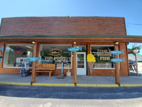 A wooden storefront with signs for "Fish & Chips" and "Fresh Smoked Fish," featuring an ice cream cone decoration.
