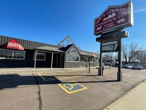 Exterior of Sioux County Livestock Co. with a sign for Backdoor Lounge, featuring a parking space for disabled access.
