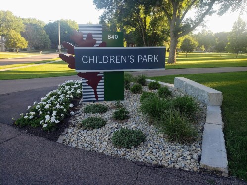 Sign for Children's Park with flowers and greenery in a well-maintained landscape.