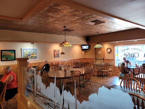 A cozy café interior with wooden chairs, tables, and stained glass lamps, featuring patrons enjoying their meals.
