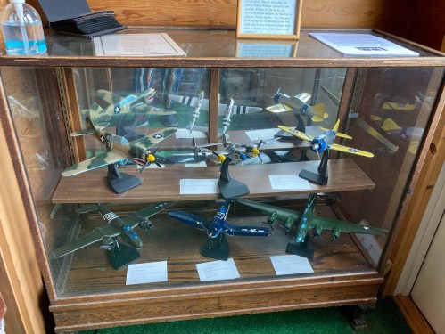 A display case containing various model airplanes, showcasing different military aircraft in detailed designs.