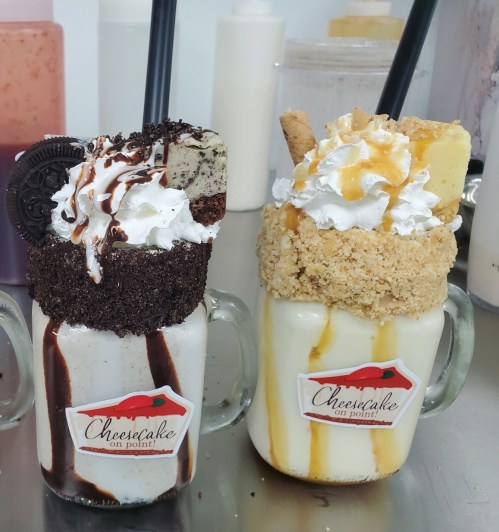 Two decadent milkshakes in mason jars, topped with whipped cream, cookies, and drizzles of chocolate and caramel.