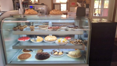 A display case filled with various desserts, including pies, cakes, and pastries, all beautifully arranged.