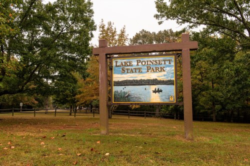 Sign for Lake Poinsett State Park, featuring a scenic lake view and trees in the background.