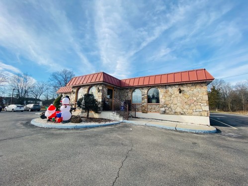 A stone building with a red roof, featuring holiday decorations outside, including Santa and a snowman.