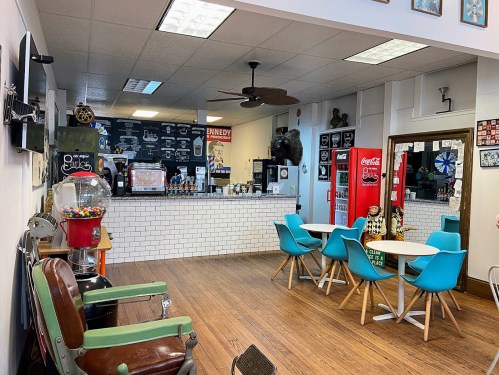 A cozy café interior featuring colorful chairs, a gumball machine, and a counter with a menu on the wall.