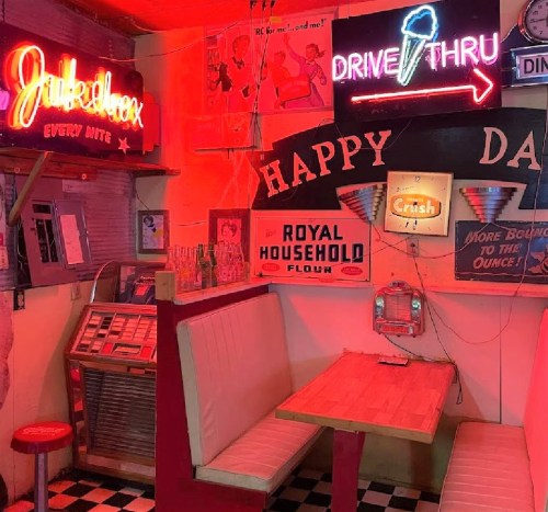 A retro diner interior with neon signs, a jukebox, and a cozy booth, featuring vibrant colors and nostalgic decor.