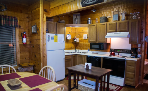 Cozy wooden kitchen with a dining table, equipped with a fridge, stove, microwave, and rustic decor.