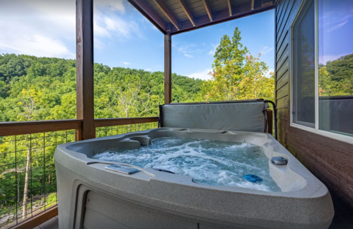 A hot tub on a balcony with a scenic view of green hills and a blue sky.