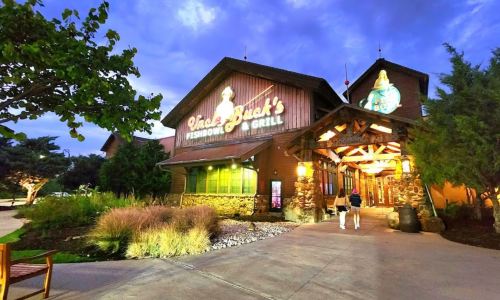 A rustic restaurant exterior with a sign reading "Uncle Buck's Fishbowl & Grill," surrounded by greenery and evening sky.