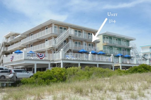 A beachside hotel with multiple units, featuring outdoor seating and umbrellas, labeled "Unit 32-4."