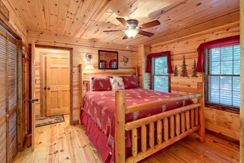 Cozy wooden bedroom with a log bed, red bedding, and natural wood walls, featuring a ceiling fan and windows.