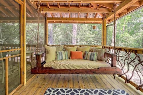 A cozy swing bed with colorful pillows on a screened porch surrounded by trees.
