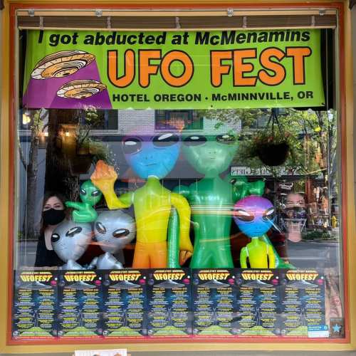 Colorful window display featuring inflatable aliens and a sign for UFO Fest at Hotel Oregon, McMinnville, OR.