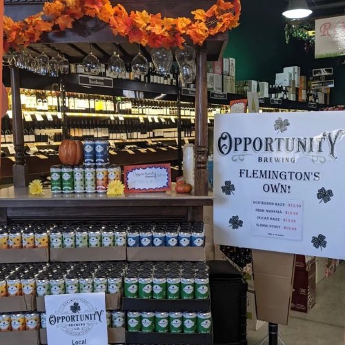 A display of Opportunity Brewing products, featuring cans and bottles, with autumn decorations and a sign highlighting local offerings.