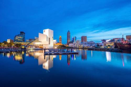 City skyline at dusk reflecting on water, featuring modern architecture and colorful lights in Cleveland, Ohio.