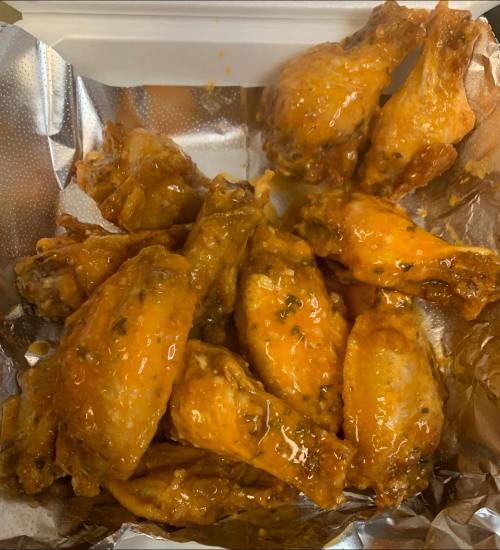 A container filled with golden-brown chicken wings coated in a spicy sauce.