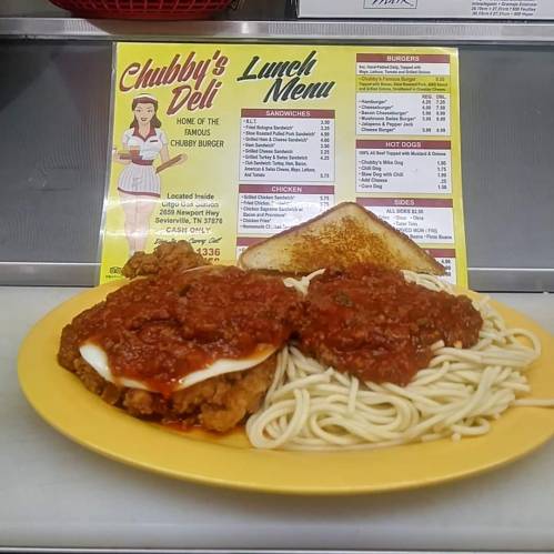 A plate of chicken topped with marinara sauce, served with spaghetti and toast, alongside a lunch menu from Chubby's Deli.