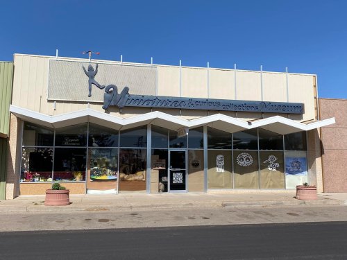 Front view of the Minotaur's & Curious Collections Museum, featuring a unique architectural design and colorful window displays.