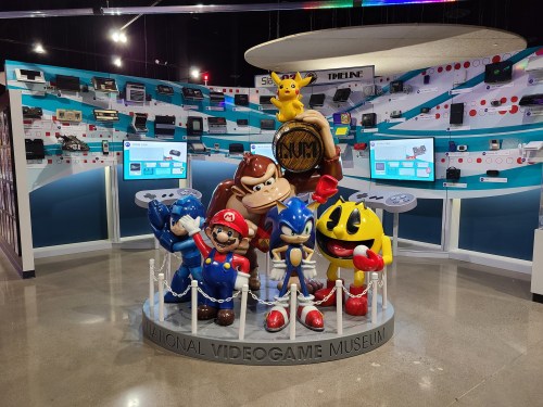 Statues of iconic video game characters, including Mario, Sonic, and Pac-Man, in a museum exhibit.