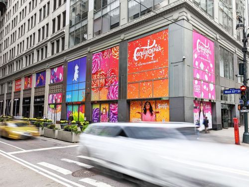 Colorful storefront with vibrant murals and advertisements, featuring a mix of artistic designs and a busy street scene.