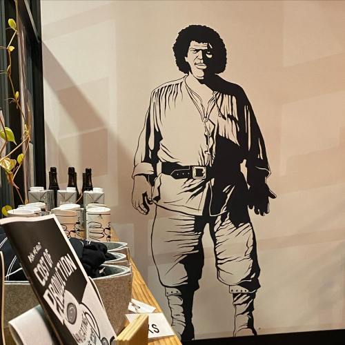 A large wall mural of a man in historical clothing, standing confidently with a shadow cast behind him.