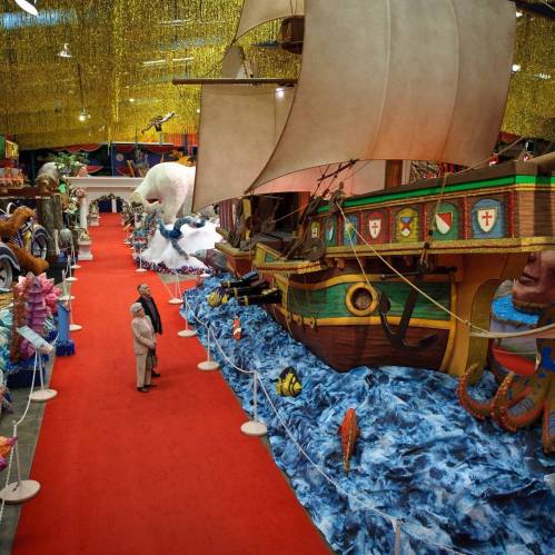 A colorful parade float display featuring a large ship and various sea-themed decorations in a festive indoor setting.
