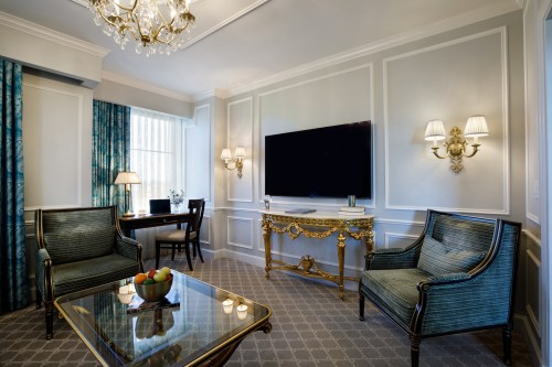 Luxurious hotel room featuring elegant furniture, a large TV, and a stylish table with a fruit bowl.