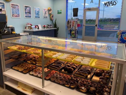 A display case filled with various donuts and pastries in a brightly lit bakery.