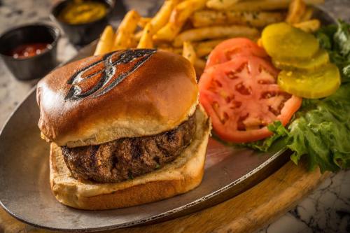 A juicy burger with lettuce, tomato, and pickles, served with crispy fries and dipping sauces on the side.