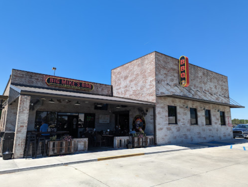 Exterior of Big Mike's BBQ restaurant with a brick facade and a clear blue sky. Outdoor seating visible.