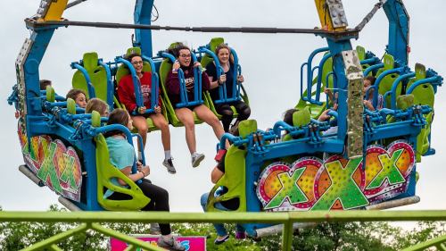 A group of excited people on a colorful amusement park ride, suspended high above the ground, enjoying the thrill.
