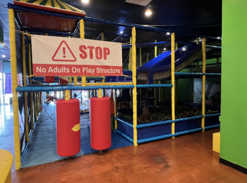 Indoor play structure with colorful nets, slides, and a sign stating "STOP: No Adults On Play Structure."