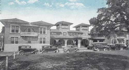 Historic building with a vintage architectural style, featuring multiple stories and classic cars parked in front.