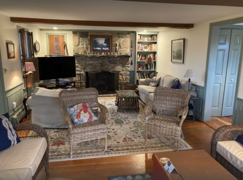 Cozy living room with stone fireplace, comfortable seating, bookshelves, and warm lighting.