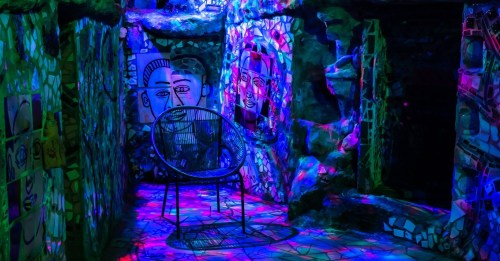 A colorful, illuminated room with vibrant murals and a single chair, creating a surreal, artistic atmosphere.