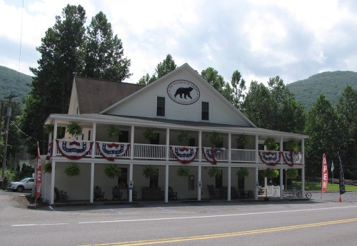 A large, white building with a bear logo, decorated with red, white, and blue bunting, surrounded by trees.