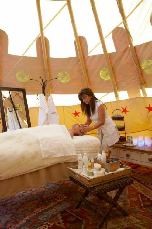 A serene spa setting inside a tent, with a therapist giving a facial to a client on a massage table.