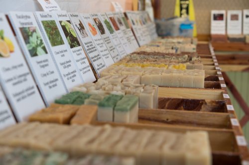 A display of various handmade soaps arranged in rows, with labels describing their ingredients and scents.