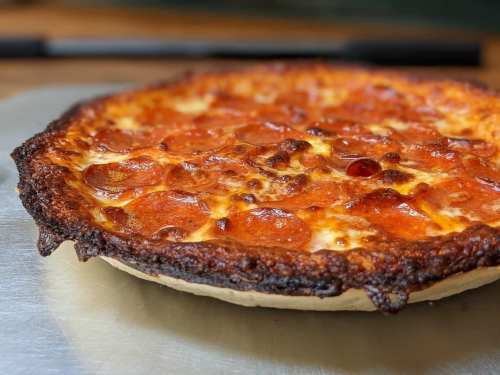 A freshly baked pepperoni pizza with a crispy crust and melted cheese, resting on a silver pizza tray.